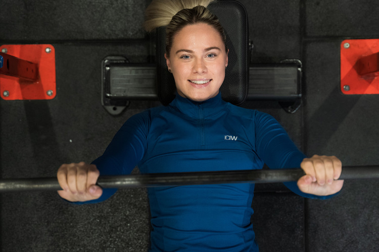 Kvinna kör skivstång liggande på gymmet